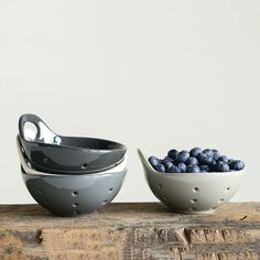 two bowls filled with blueberries sitting on top of a wooden table next to each other