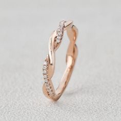 a rose gold wedding ring with diamonds on it's sides, sitting on a white surface