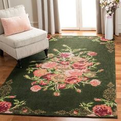 a living room area with a chair, rug and flowers on the floor in front of a window