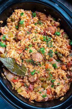 a black crock pot filled with rice and meat