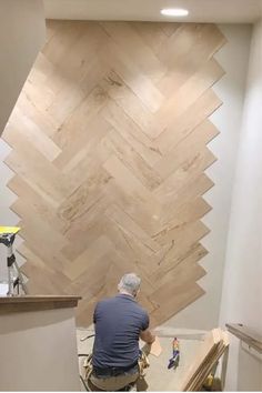 Person installing a herringbone wood pattern on a wall. Walls With Shelves, Rough Wood