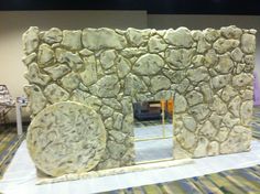 a fake stone building made out of rocks on display in a room with carpeted flooring