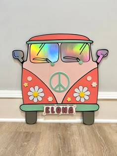 an orange and pink vw bus with peace sign on the front is sitting on a wood floor