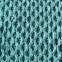 a close up view of a blue knitted blanket with wavy lines on the edges