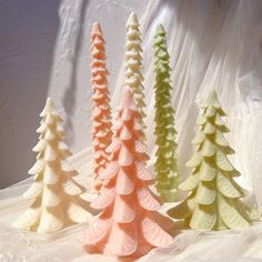 three different colored trees sitting next to each other on a white cloth covered tablecloth