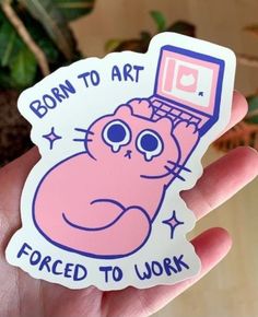 a hand holding a pink sticker with an image of a cat using a laptop