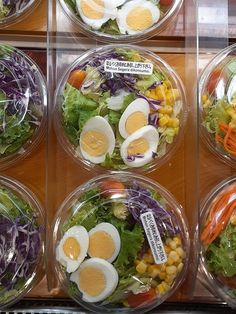 several plastic bowls filled with different types of salads and eggs on top of each other