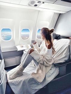 a woman sitting on an airplane seat with her feet up in the air and looking out the window