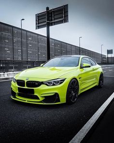 a bright yellow bmw is parked on the side of the road in front of a building