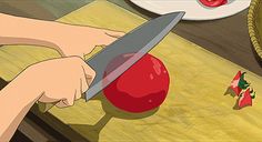 a person cutting up a tomato with a knife on a cutting board next to a bowl