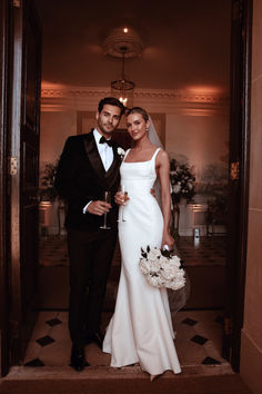 a bride and groom pose for a photo in the doorway to their wedding reception room