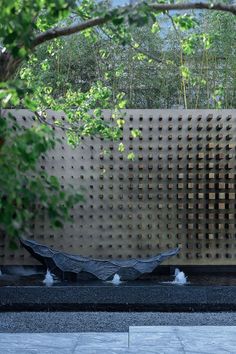 a sculpture in the shape of a boat sits on a stone floor next to a tree