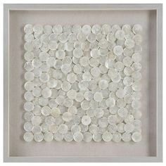 a white framed artwork with lots of coins in it's shadow on the wall