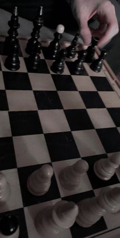 a man is playing chess on a checkered board with black and white pawns