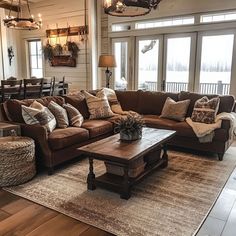 a living room filled with lots of furniture next to a wooden table and windows on the wall