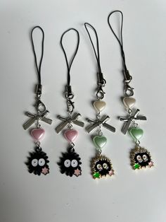 four charms with different designs on them are hanging from cords in front of a white surface