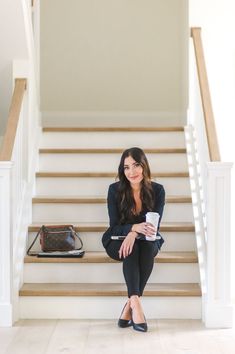 a woman sitting on the stairs holding a coffee cup