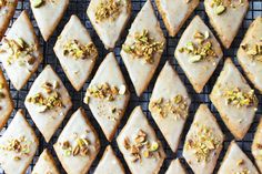 a bunch of cookies that are sitting on a cooling rack with nuts and pistachio toppings