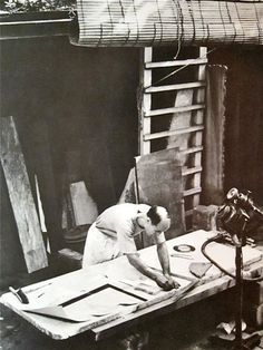 an old black and white photo of a man working on a piece of wood in his workshop