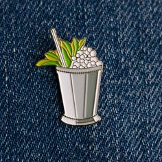 a pin with a drink in it sitting on some blue jeans