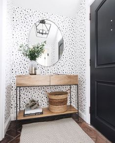 the entryway is decorated in black and white polka dot wallpaper with a wooden console