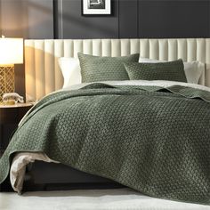 a bed with a green bedspread and pillows