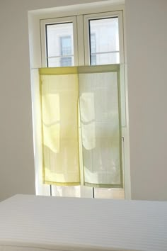 a bed sitting under two windows next to a window with yellow drapes on it