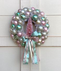 a christmas wreath hanging on the side of a door with ornaments around it and ribbon