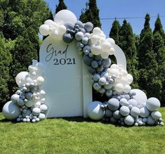 a large white sign with balloons attached to it in the middle of a grassy area