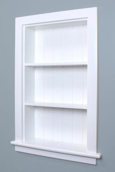 an empty white book shelf against a gray wall