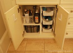 an open cabinet in the corner of a kitchen with white cabinets and drawers on both sides