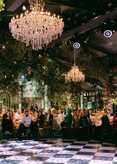 people sitting at tables with chandeliers hanging from the ceiling