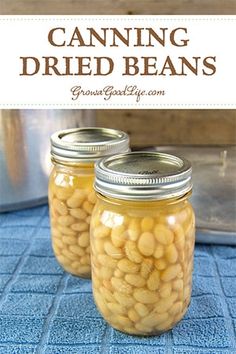 two jars filled with canned beans sitting on top of a blue mat next to an open can