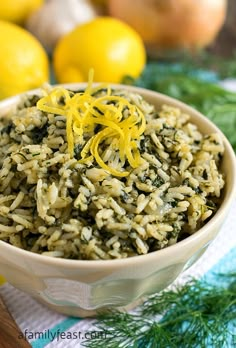 a bowl filled with rice and lemons on top of a table next to lemons