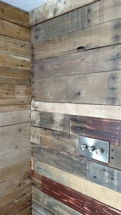 a bathroom with wooden walls and a toilet in the corner next to a wall made out of wood planks