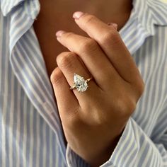 a woman wearing a ring that has a pear shaped diamond on the middle of it