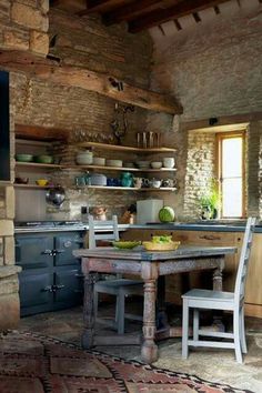 a rustic kitchen with an old table and chairs in the center, surrounded by stone walls