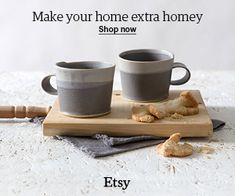 two coffee cups sitting on top of a wooden cutting board