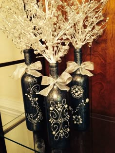 three vases with flowers in them are sitting on a table next to each other