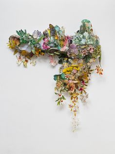 a piece of art that is made out of flowers and other things on the wall