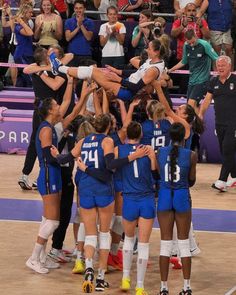 a group of women's volleyball players huddle together in the middle of a huddle