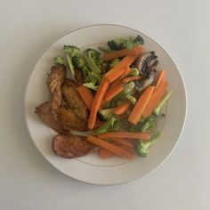 a white plate topped with chicken, broccoli and carrots next to mushrooms