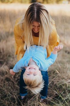 a woman is playing with a small child in the middle of some tall brown grass