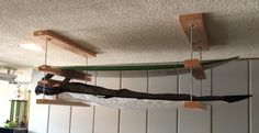 a man hanging upside down on a surfboard in a room with white cupboards