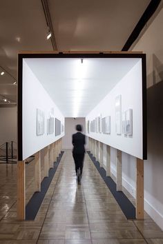 a person walking down a long hallway with pictures on the wall and floor in front of them