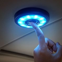 a hand is pointing at a blue light on the ceiling