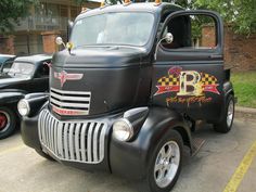 an old black truck parked in a parking lot