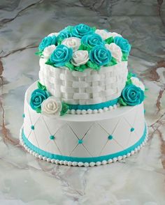 two tiered wedding cake decorated with blue and white flowers on marble counter topper