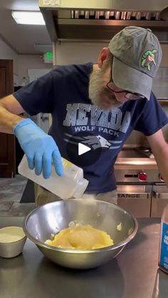 a man in a kitchen preparing food on top of a metal counter with blue gloves