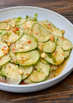 a white bowl filled with sliced cucumbers on top of a wooden table